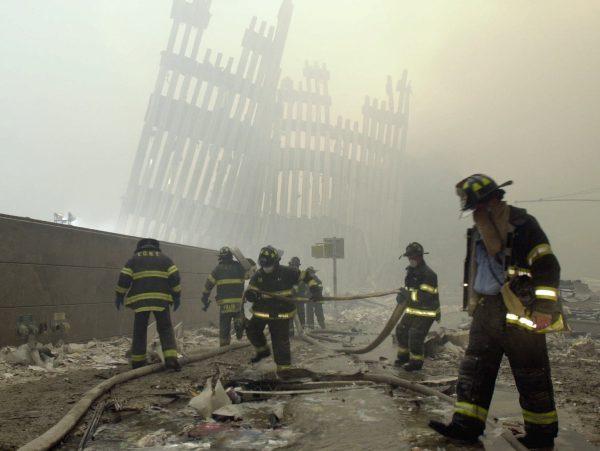The skeleton of the World Trade Center twin towers in the background. Firefighters work amid debris on Cortlandt St. after the terrorist attacks in New York City, on Sept. 11, 2001 (Mark Lennihan/AP)