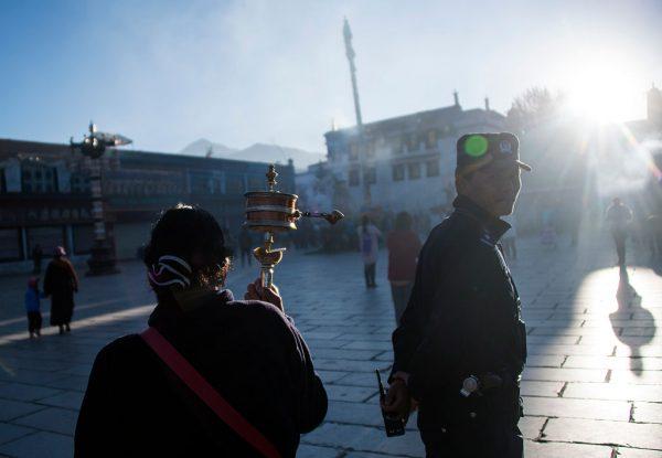 A pilgrim spinning her prayer wheel next to a policeman in front of the Jokhang Temple in the regional capital Lhasa, Tibet on September 10, 2016. (JOHANNES EISELE/AFP/Getty Images)