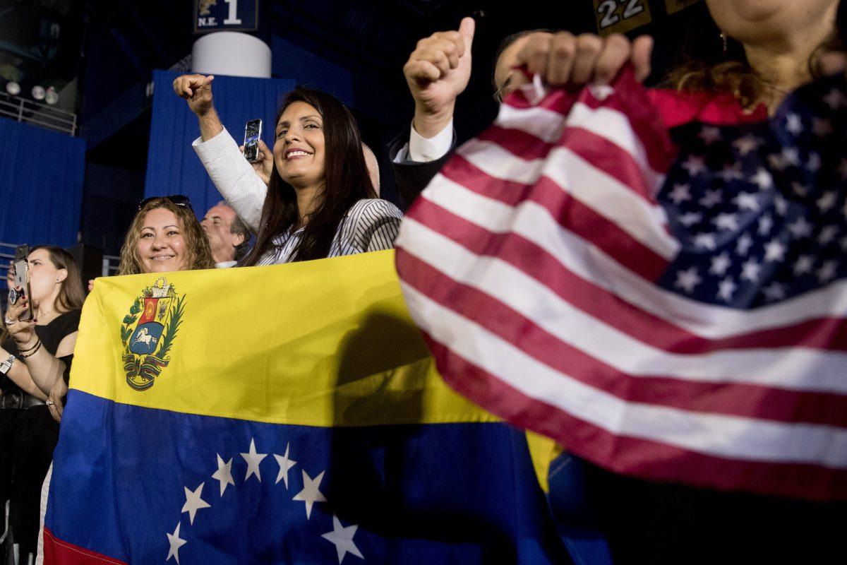  Members of the audience wave Venezuelan and American flags as President Donald Trump speaks to a Venezuelan American community in Miami, Feb. 18, 2019 (AP Photo/Andrew Harnik)