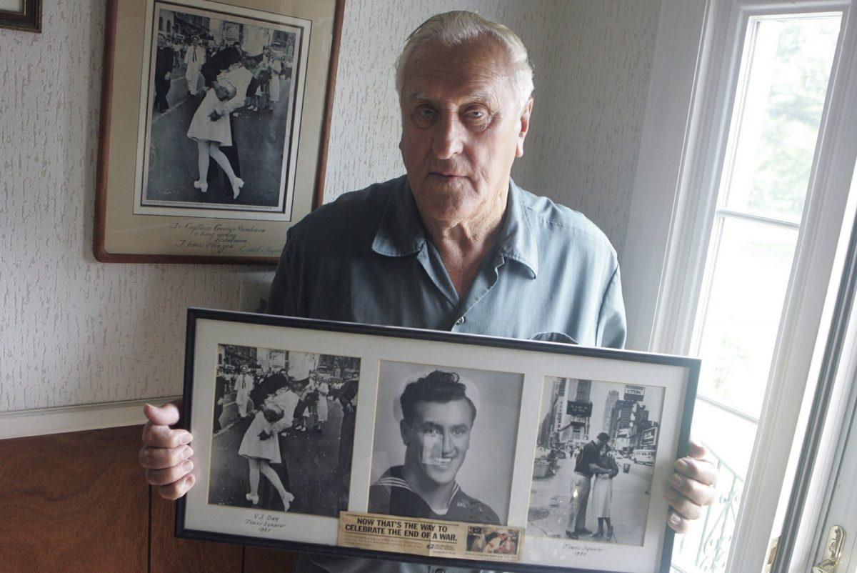 George Mendonsa poses for a photo in Middletown, R.I., holding a copy of the famous Alfred Eisenstadt photo of Mendonsa kissing a woman in a nurse's uniform in Times Square on Aug. 14, 1945, while celebrating the end of World War II, left. (Connie Grosch/Providence Journal via AP)