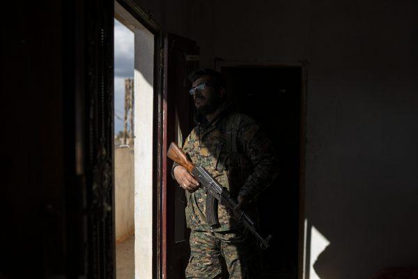 A U.S.-backed Syrian Democratic Forces (SDF) fighter walks out of a building recently taken by SDF as the fight against ISIS continues in the village of Baghouz, Syria, on Feb. 17, 2019. (Felipe Dana/AP)