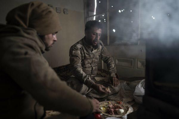 U.S.-backed Syrian Democratic Forces (SDF) fighters eat in a building as the fight against ISIS continues in the village of Baghouz, Syria, on Feb. 17, 2019. (Felipe Dana/AP)