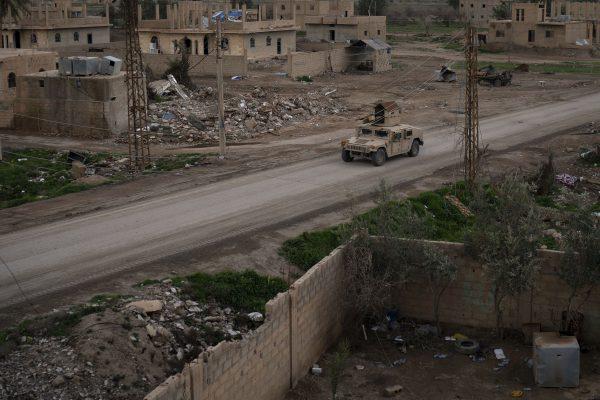 A Humvee drives in a village recently retaken from ISIS by U.S.-backed Syrian Democratic Forces (SDF) near Baghouz, Syria, on Feb. 17, 2019. (Felipe Dana/AP)