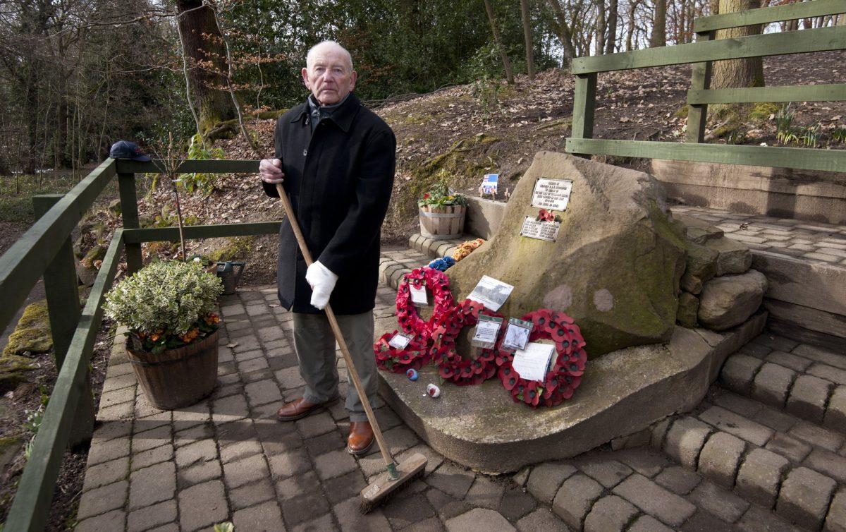 Tony Foulds holds a broom as he stands next to a memorial honoring 10 U.S. airmen who died in a plane crash in Endcliffe Park, Sheffield, England, Wednesday, Feb. 13, 2019. (Rui Vieira/AP Photo)