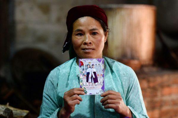 Ly Thi My, a Vietnamese mother posing with a photograph of her missing daughter Di at her house in Meo Vac, a mountainous border district between Vietnam's Ha Giang province and China, on Oct. 27, 2018. (Nhac Nguyen/AFP/Getty Images)