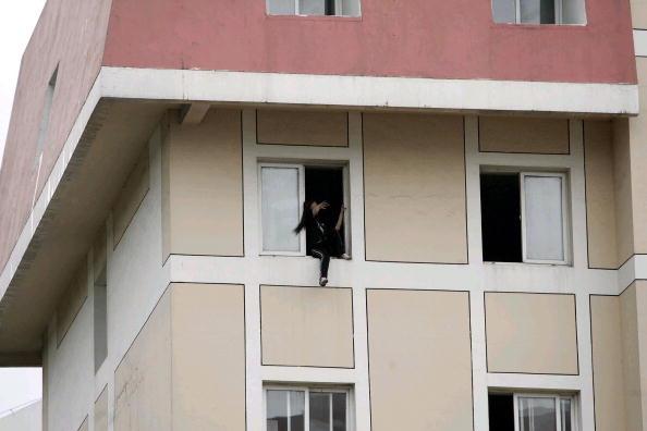 A college student threatens to jump from the window of her dormitories in Shenyang, in northeastern China's Liaoning Province on June 4, 2005, after failing her examinations, but was later coaxed down by her parents. (STR/AFP/Getty Images)