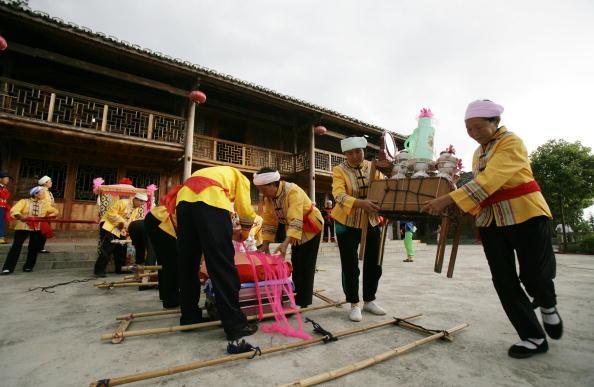 Tujia ethnic people prepare to carry the bride's dowry to the home of the groom during a wedding in Qianjiang Tujia and Miao Autonomous County of Chongqing Municipality, China, on Aug. 2, 2008. (China Photos/Getty Images)
