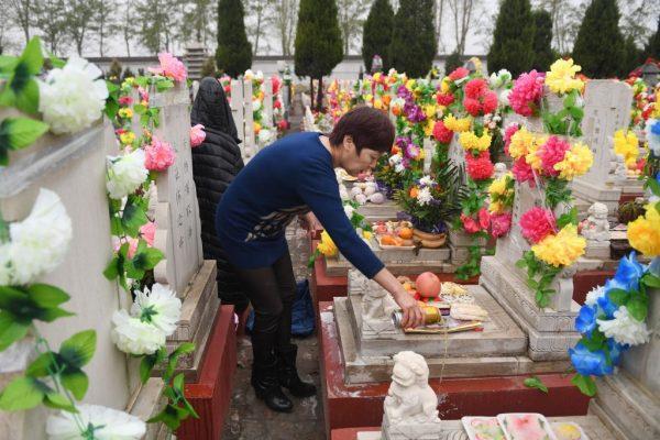 A woman pours beer on her husband's grave during the Qingming Festival, also known as Tomb Sweeping Day, at a cemetery in Beijing on April 5, 2018. (Greg Baker/AFP/Getty Images)