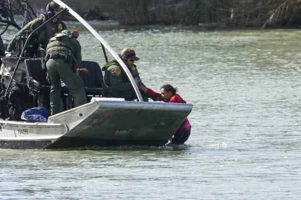 Agents on a U.S. Customs and Border Protection boat rescue a woman and child who got stuck attempting to cross the Rio Grande into the United States illegally at Eagle Pass, Texas, on Feb. 16, 2019. (Charlotte Cuthbertson/The Epoch Times)