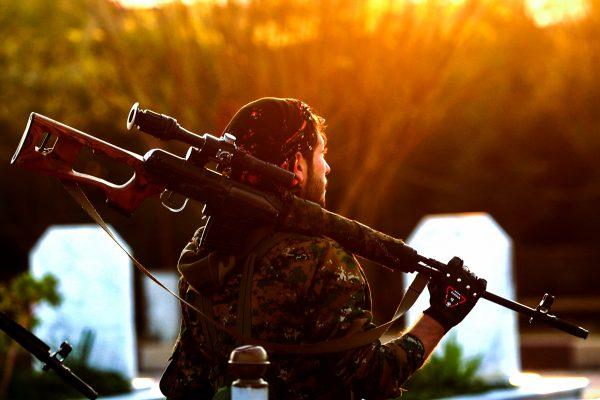 A fighter with the Syrian Democratic Forces (SDF), a US ally in the fight against ISIS, holds a sniper rifle on his shoulder as he attends the funeral of a slain Kurdish commander in Qamishli, Syria, on Dec. 6, 2018. (Delil Souleiman/AFP/Getty Images)
