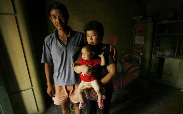 AIDS sufferers Cao Xiaonian (L) and his wife Zhou Xiaoneng (R) hold their 9-month-old baby in their village home in China's southern Henan province, on  August 2, 2006. (Peter Parks/AFP via Getty Images)
