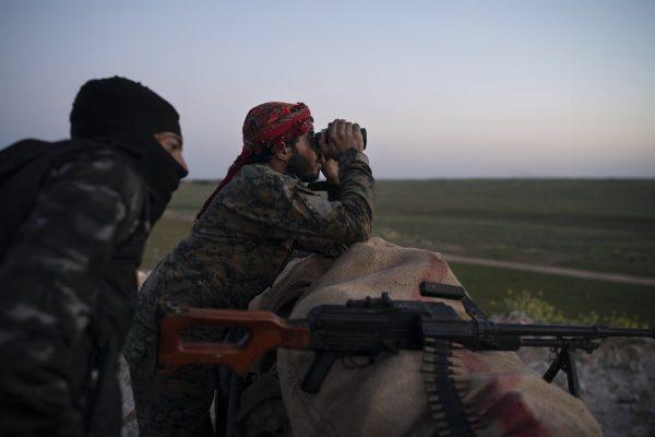 U.S.-backed Syrian Democratic Forces (SDF) fighters watch as an airstrike hits territory still held by ISIS militants in the desert outside Baghouz, Syria, on Feb. 19, 2019. (Felipe Dana/AP Photo)