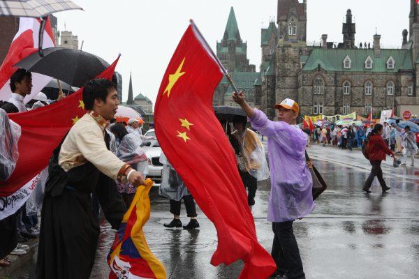 A man with a large Chinese flag blocks a Tibetan protester during a visit by then-Chinese leader Hu Jintao to Ottawa on June 24, 2010. (The Epoch Times)