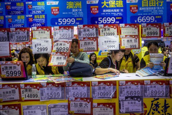 People check on travel packages offered by travel agencies during the Guangzhou International Travel Fair in Guangzhou in China's Guangdong Province on March 3, 2018. Travelers in China were blocked from buying plane tickets 17.5 million times in 2018 as a penalty for failing to pay fines or other offenses. The Chinese regime reported on penalties imposed under a controversial "social credit" system. (Chinatopix via AP)