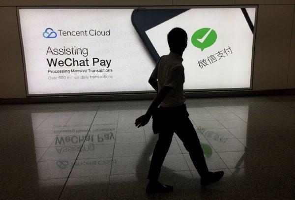 This photo taken on August 21, 2017 shows a man walking at Hong Kong's international airport past an advertisement for the WeChat social media platform owned by China's Tencent company. / AFP PHOTO / Richard A. Brooks (Photo credit should read RICHARD A. BROOKS/AFP/Getty Images)