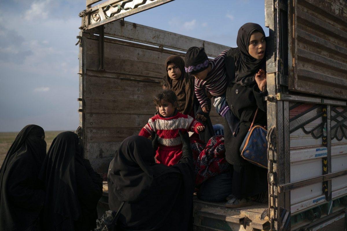 Women and children exit the back of a truck, part of a convoy evacuating hundreds out of the last territory held by Islamic State militants in Baghouz, eastern Syria, on Feb. 22, 2019. (Felipe Dana/AP Photo)