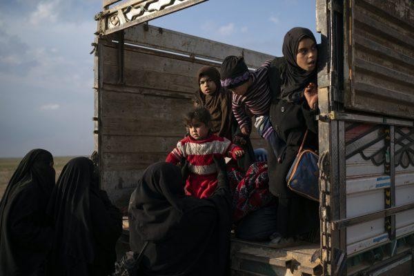 Women and children exit the back of a truck, part of a convoy evacuating hundreds out of the last territory held by ISIS in Baghouz, eastern Syria, on Feb. 22, 2019. (Felipe Dana/AP Photo)