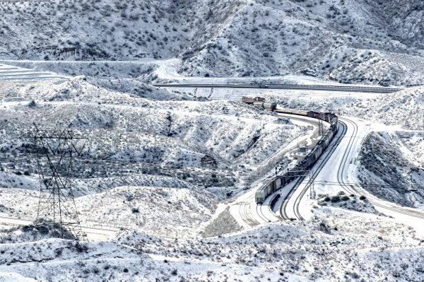 A train rolls along the snow-covered hills in the Cajon Pass near Highway 138 in Phelan, Calif., on Feb. 21, 2019. (Watchara Phomicinda/The Orange County Register via AP)