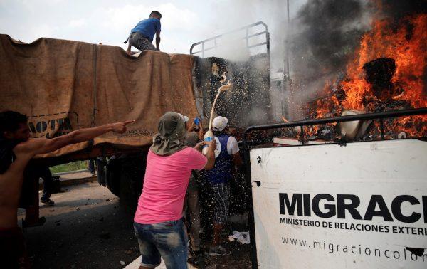 Opposition supporters unload humanitarian aid from a truck that was set on fire after clashes between opposition supporters and Venezuela's security forces at the Francisco de Paula Santander bridge on the border line between Colombia and Venezuela as seen from Cucuta, Colombia, Feb. 23, 2019. (Marco Bello/Reuters)