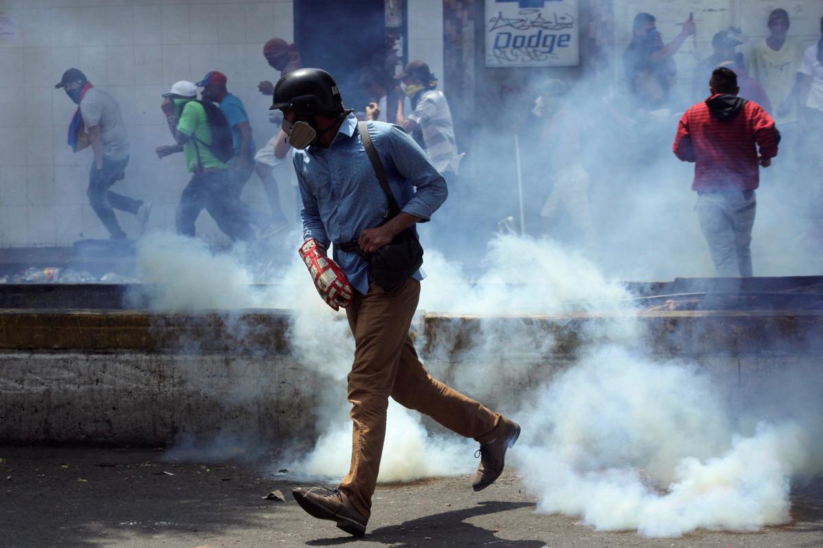Demonstrators run away from tear gas while clashing with Venezuela's security forces during a rally to demand President Nicolas Maduro to allow humanitarian aid to enter the country in San Antonio del Tachira, Venezuela, on Feb. 23, 2019. (Reuters/Carlos Eduardo Ramirez)