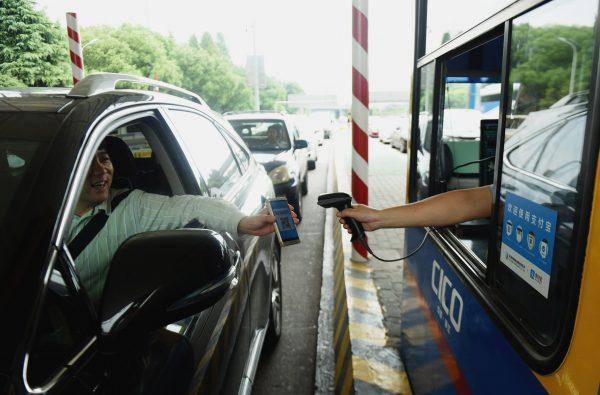 A driver uses his smartphone to pay the highway toll by way of Alipay, an app of Alibaba's online payment service, at Pengbu toll station on the Hangzhou-Ningbo Expressway in Hangzhou, Zhejiang Province, China on Sept. 21, 2016.