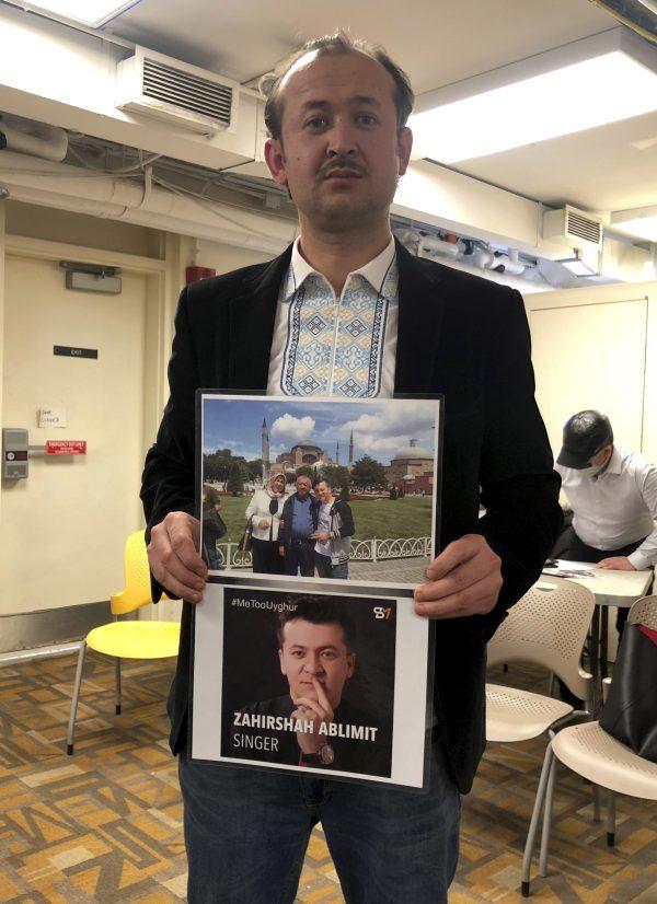 Abudwaris Ablimit holds up photos of his parents and brother during a gathering to raise awareness about loved ones who have disappeared in China's far west in Washington DC on Feb. 24, 2019. (Christina Larsen/AP)