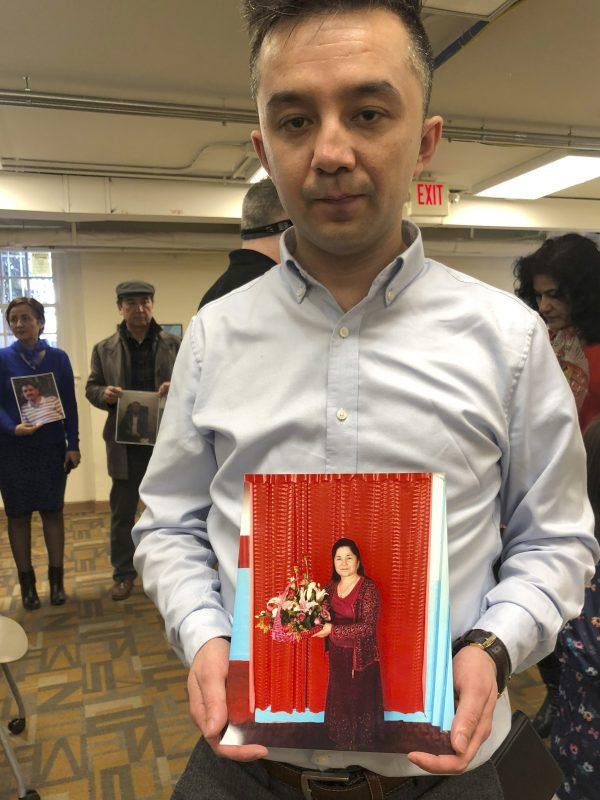 Ferkat Jawdat holds up a photo of his mother during a gathering to raise awareness about loved ones who have disappeared in China's far west, in Washington DC on Feb. 24, 2019. (Christina Larsen/AP)