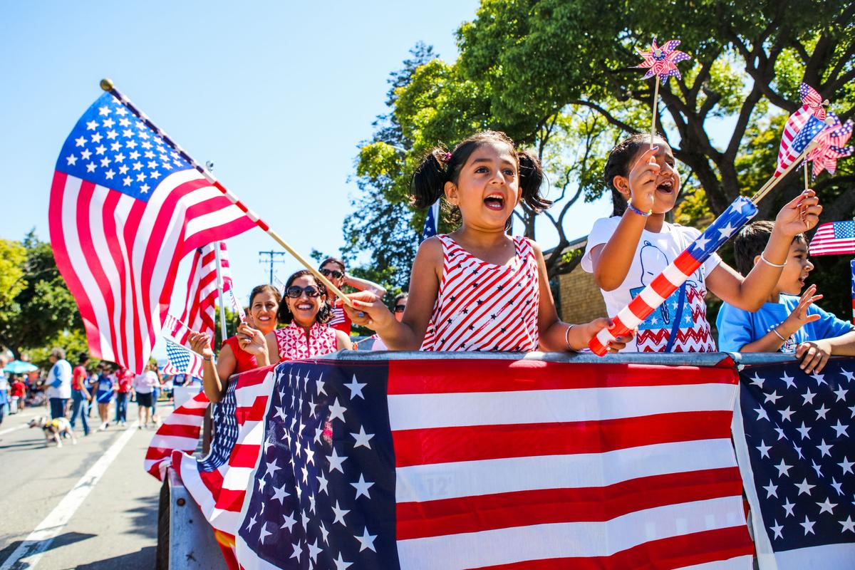 People wave American flags as they ride through 4th of July Parade in Alameda, Calif. on Jul. 4, 2016. (Gabrielle Lurie/AFP/Getty Images)