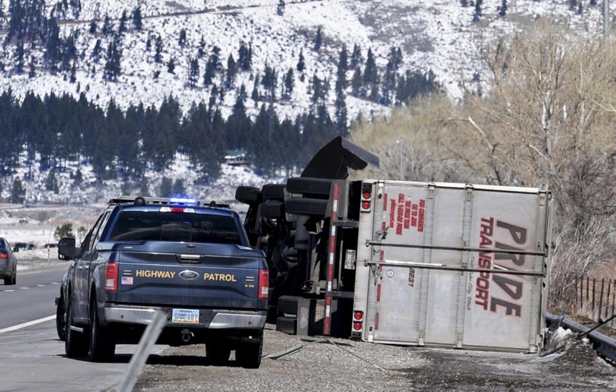 The Nevada Highway Patrol parks next to a rolled over high profile vehicle on the Interstate 580 south of Reno, Nev., on Feb 25, 2019. (Andy Barron/Reno Gazette-Journal via AP)