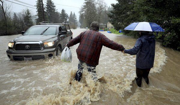 Residents along Armstrong Woods Road head back to their home after the road became impassable to most vehicles in Guerneville, Calif., on Feb. 26, 2019. (Kent Porter/The Press Democrat via AP)