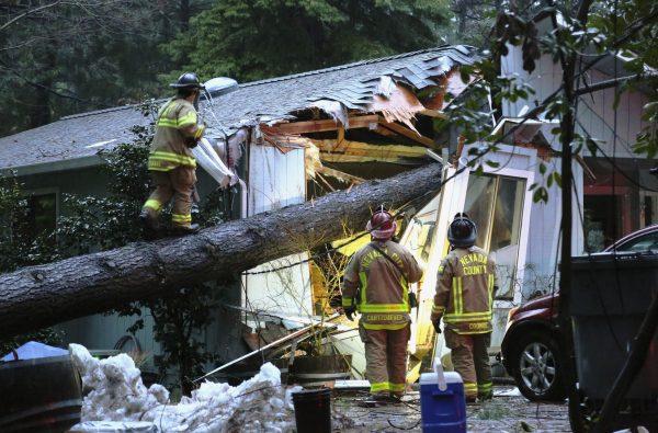 Nevada County and Nevada City firefighters work to assess a structure on Juniper Drive that sustained a tree fall, knocking out power and potentially causing a gas hazard in the process on Feb. 26, 2019. (Elias Funez/The Union via AP)