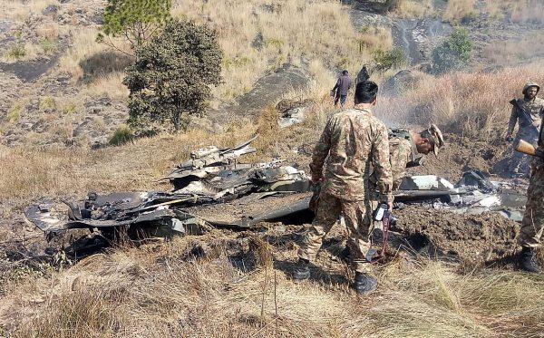 Pakistani soldiers stand next to what Pakistan says is the wreckage of an Indian fighter jet shot down in Pakistan controled Kashmir at Somani area in Bhimbar district near the Line of Control on Feb. 27, 2019. (STR/AFP/Getty Images)