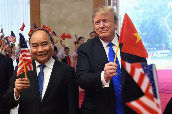 US President Donald Trump (R) holds a Vietnamese flag as Vietnam's Prime Minister Nguyen Xuan Phuc (L) waves a U.S. flag upon their arrival for a meeting at the Government Office in Hanoi on Feb. 27, 2019. (SAUL LOEB/AFP/Getty Images)
