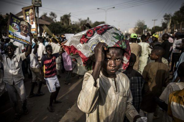 A boy cover himself with a plastic bag while All Progressives Congress Party supporters celebrate results released by the Nigerian Independent National Electoral Commission in Kano, Nigeria, on Feb. 25, 2019. (Luis Tato/AFP/Getty Images)