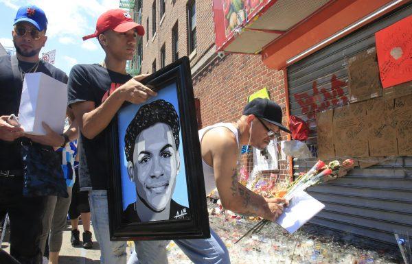 Jose Bencosme holds a painting of his cousin 15-year-old Lesandro Guzman-Feliz, a gift from celebrity artist Samil Alva, as he visits a community memorial for Feliz who was killed on June 26, 2018, in a machete attack in N.Y. (Bebeto Matthews/AP)
