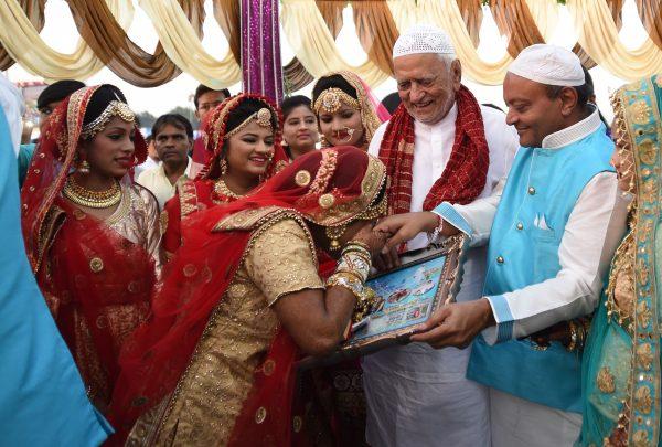 This picture taken on Dec. 24, 2017, shows an Indian Muslim bride kissing the hand of Indian businessman Maheshbhai Savani (2nd R) during a mass wedding in Surat, some 270 km from Ahmedabad. (©Getty Images | <a href="https://www.gettyimages.com/detail/news-photo/this-picture-taken-on-december-24-2017-shows-an-indian-news-photo/898186914">Sam Panthaky/AFP</a>)