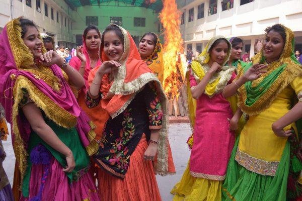 Indian college women clad in traditional Punjabi dress perform the 'giddha' folk dance around a bonfire during celebrations on the eve of the Lohri festival in Amritsar on Jan. 12, 2016. The Lohri harvest festival commemorates the winter solstice and is marked in northern India by the lighting of bonfires and the flying and battling of kites.  (©Getty Images | <a href="https://www.gettyimages.com/detail/news-photo/indian-college-women-clad-in-traditional-punjabi-dress-news-photo/504664416">Narinder Nanu/AFP</a>)