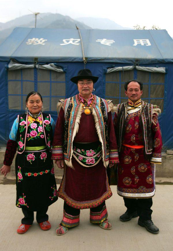 Qiang tourism promotor Mu Guangyuan (C), a 68-year-old Qiang ethnic man, his wife 67-year-old Zhou Tiancui (L), and 56-year-old Guozhuang Dancing teacher Wang Guanquan, pose dressed in traditional costumes, in front of tents at the Leigu Township on Nov. 26, 2008, in Beichuan County of Sichuan Province, China. (©Getty Images | <a href="https://www.gettyimages.com/detail/news-photo/qiang-tourism-promotor-mu-guangyuan-a-68-year-old-qiang-news-photo/83840710">China Photos</a>)