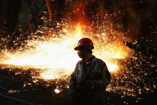 A worker with molten iron flowing up in the iron-smelting workshop at the Chengde Steel Plant in Chengde City, Hebei Province, China, on Oct. 11, 2007. (Feng Li/Getty Images)
