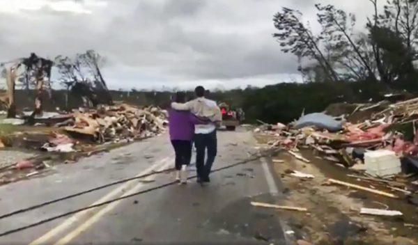 People walk amid debris in Lee County, Ala., after what appeared to be a tornado struck in the area on March 3, 2019. (WKRG-TV via AP)
