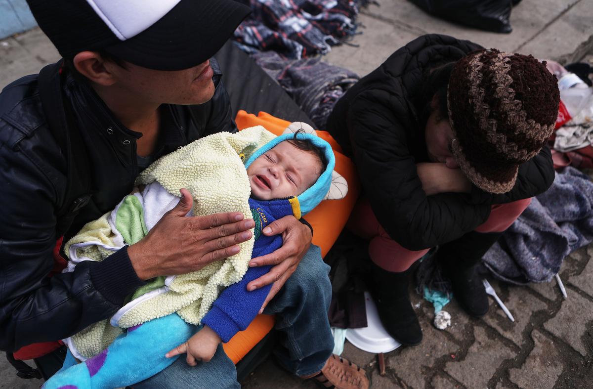 Honduran father Alexandre holds his son Karmaliel, who is sick with a fever, as mother Liselda sits next to them on the sidewalk where they were planning to sleep on Nov. 30, 2018 in Tijuana, Mexico. (Mario Tama/Getty Images)