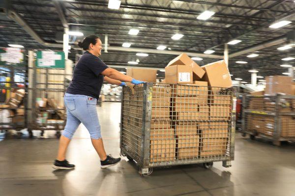 US Postal service mail handler Javiera Dabdub pushes a cart full of packages to be sorted at the US Postal service's Royal Palm Processing and Distribution Center in Opa Locka, Florida on December 17, 2018. (Joe Raedle/Getty Images)