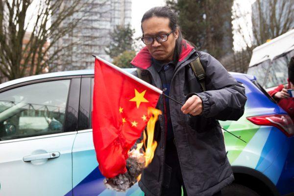 Demonstrator Kuang Yang burns a Chinese flag to protest human rights abuses committed by the country's communist regime, outside British Columbia Supreme Court, in Vancouver, Canada, on March 6, 2019. (Jason Redmond/AFP)