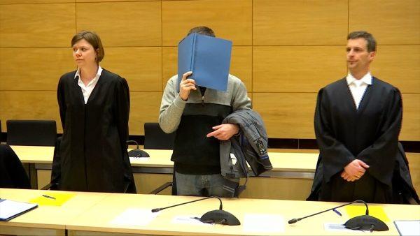 Klaus O. arriving in the courtroom at Bielefeld district court, covering his head with a binder in Bielefeld, Germany, on March 8, 2019. (Still Image/Reuters)