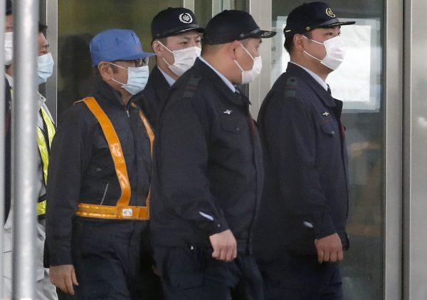 Former Nissan Chairman Carlos Ghosn, in blue cap, walks out with security guards from Tokyo Detention Center in Tokyo on March 6, 2019. (Eugene Hoshiko/AP Photo)