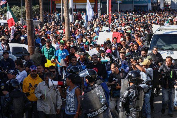 Migrants push past riot police at the foot of a bridge leading from the migrant camp to the El Chaparral pedestrian entrance at the San Ysidro border crossing in Tijuana, Mexico, on Nov. 25, 2018. (Charlotte Cuthbertson/The Epoch Times)