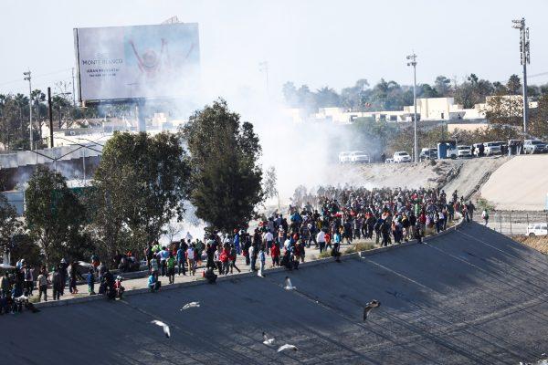 Migrants begin to retreat as U.S. law enforcement uses tear gas to repel their efforts to cross illegally into the United States, just west of the San Ysidro crossing in Tijuana, Mexico, on Nov. 25, 2018. (Charlotte Cuthbertson/The Epoch Times)