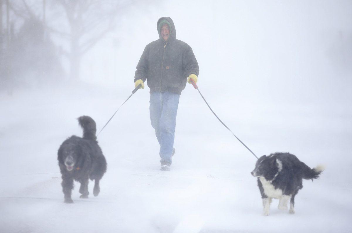 Tom Skaar of Cheyenne laughs while walking his dogs on House Avenue during a blizzard in Cheyenne, Wyo, on March 13, 2019. (Jacob Byk/The Wyoming Tribune Eagle via AP)