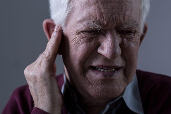 An old man suffing from tinnitus (Photographee.eu/Shutterstock)