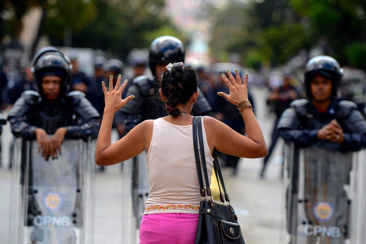 A supporter of Venezuelan opposition leader and self-proclaimed acting president Juan Guaidó, stands in front of a line of National Bolivarian riot police officers during a demo in Caracas on March 9, 2019. (Matias Delacroix/AFP/Getty Images)